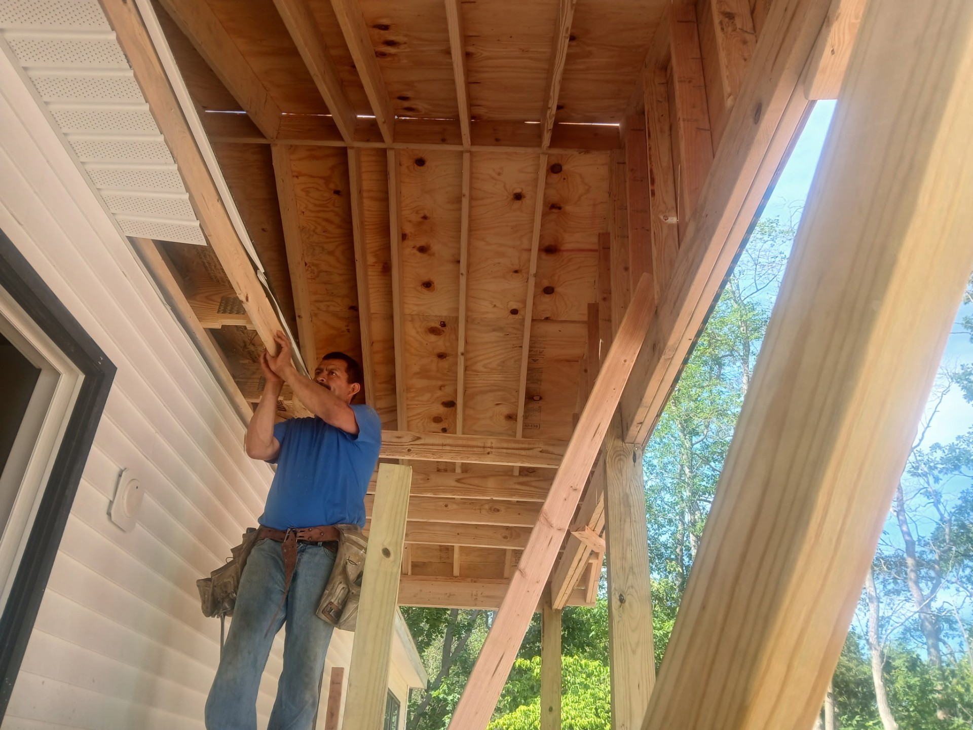 Carpenter framing a covered porch ceiling